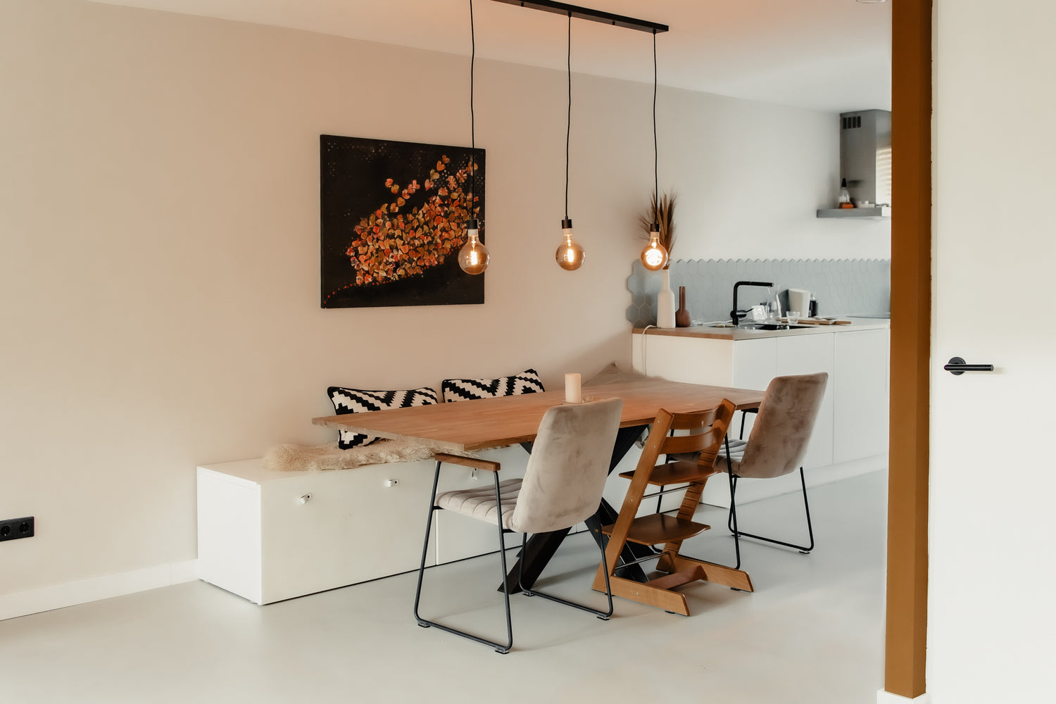 Eethoek met houten tafel, hanglampen en keuken in een moderne woonruimte.