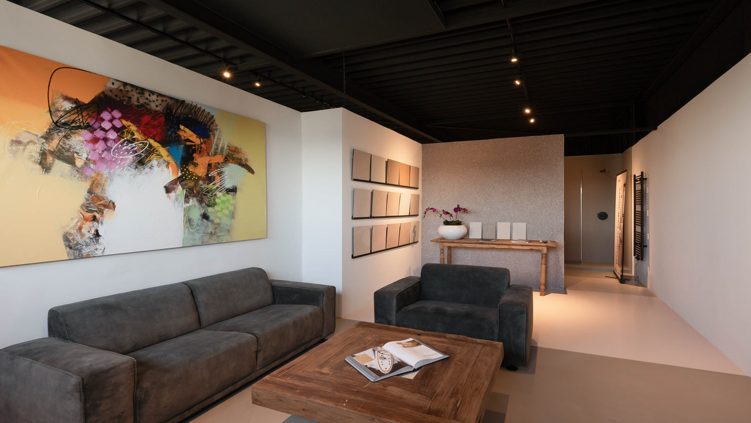 Glad gietvloeren showroom interieurzaak met groot kleurrijk schilderij, donkergroen bankstel, zwart plafond