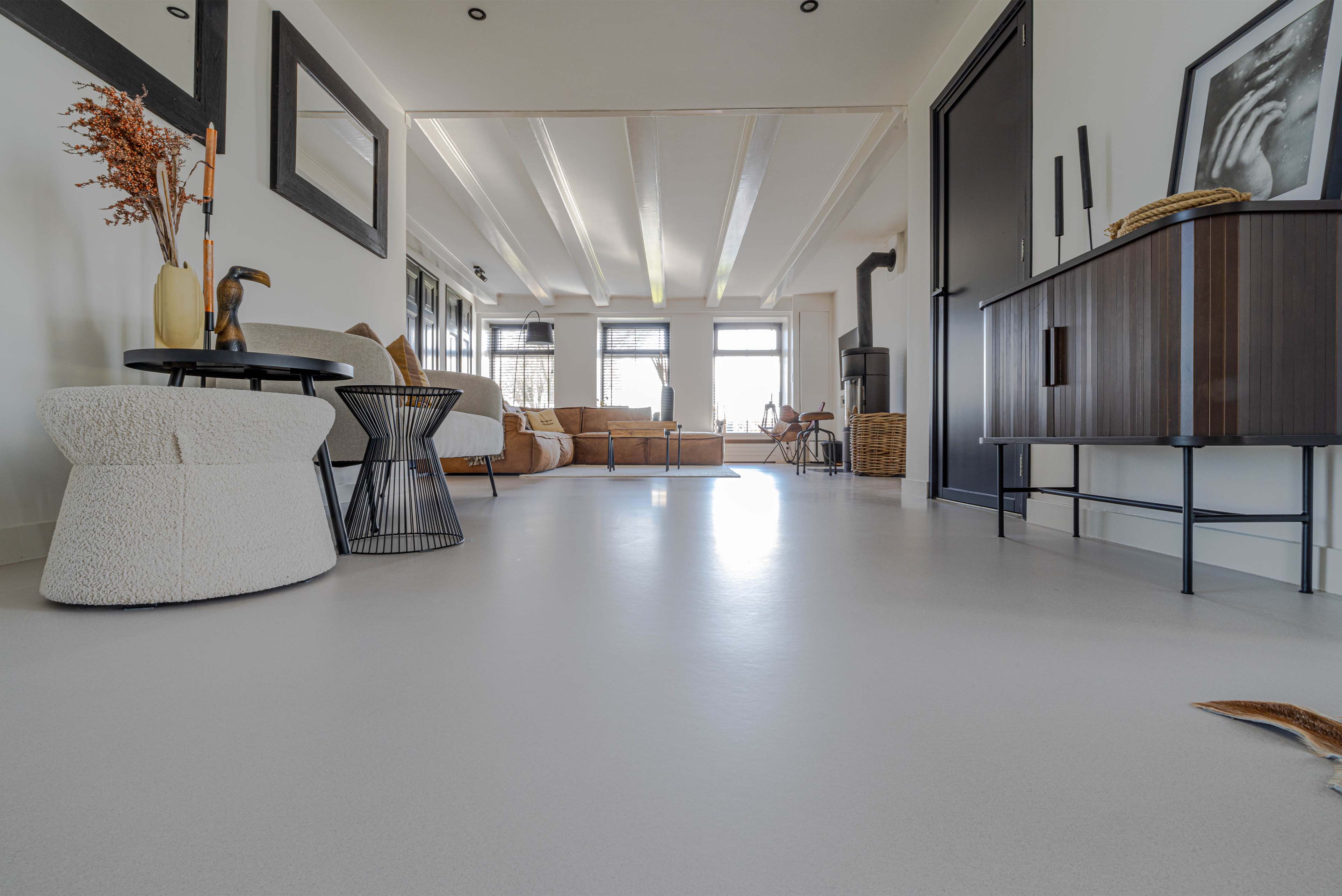 Stijlvolle woonkamer met lichte vloer, moderne meubels en warme accenten in een ruim en licht interieur.