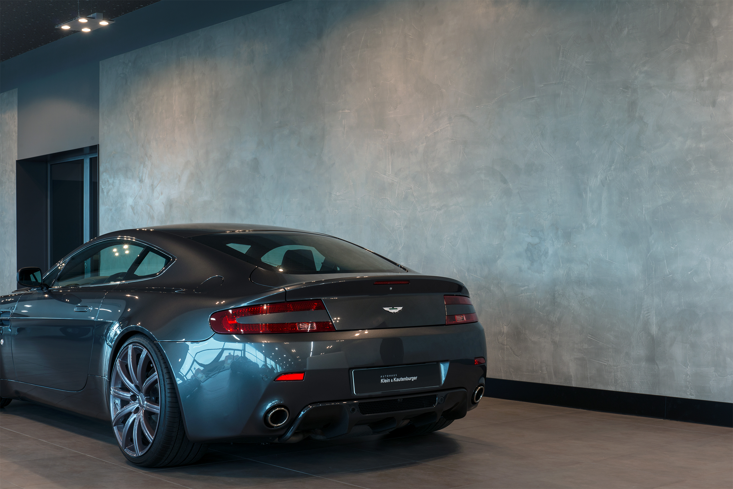 Een Aston Martin auto die voor een muur staat die is afgewerkt met Pandomo Studio