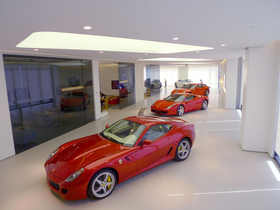 Showroom met meerdere rode Ferrari’s op een strakke lichtgrijze gietvloer.